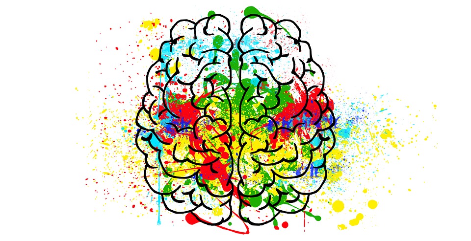 A black outline of a brain with a variety of paint splatters in lots of different colours.