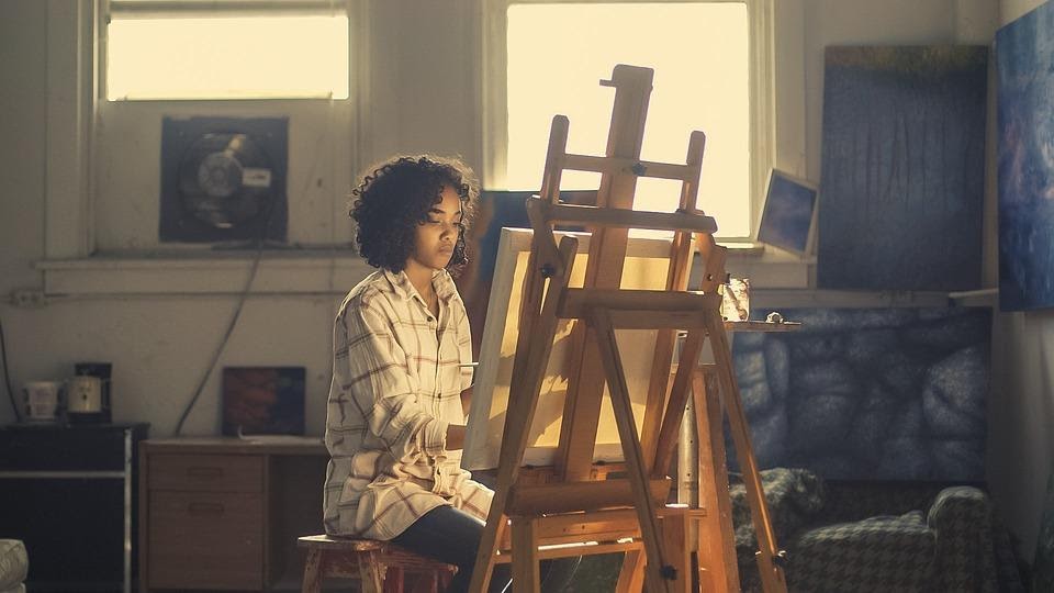 A woman sitting alone painting a canvas