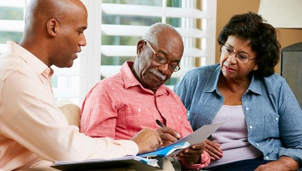 A young man helping an elderly man and woman with a care plan