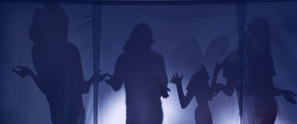 A dark blue translucent fabric with shadow silhouettes of people holding their arms out.