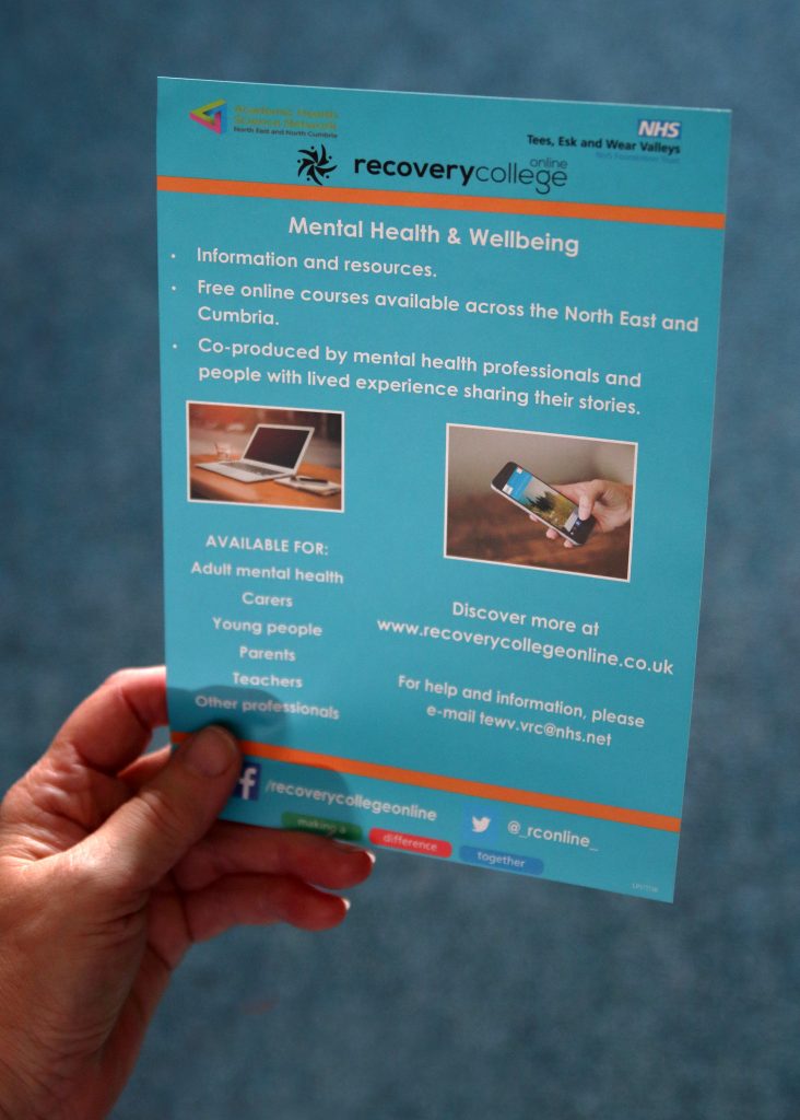 Image of a hand holding a Recovery College Online information flyer.