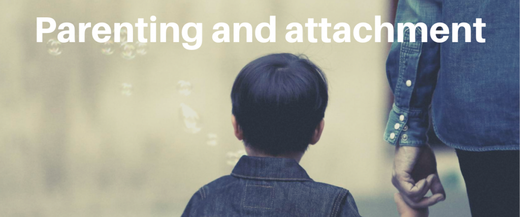 The back of a young child who is blowing bubbles and holding the hand of a carer with the words parenting and attachment.