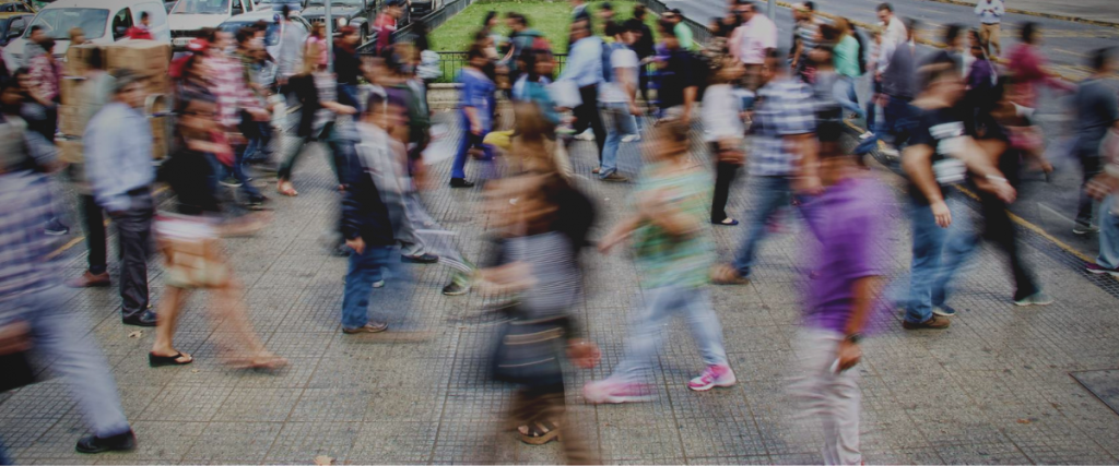 A very busy road crossing with lots of people going in both directions that look blurry indicating their movement.