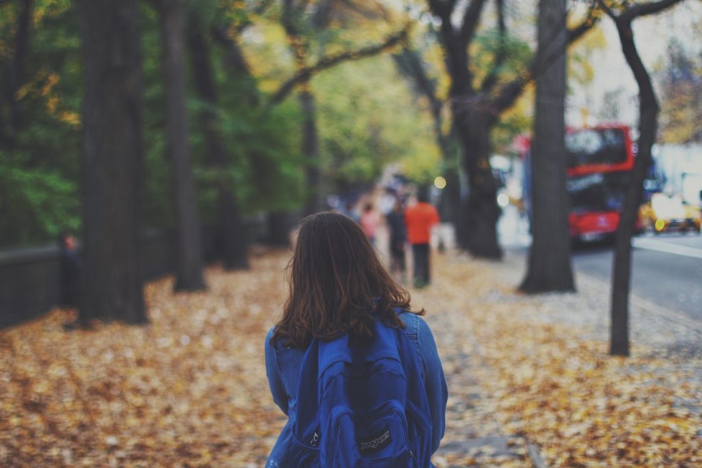 Young person walking outside alone.