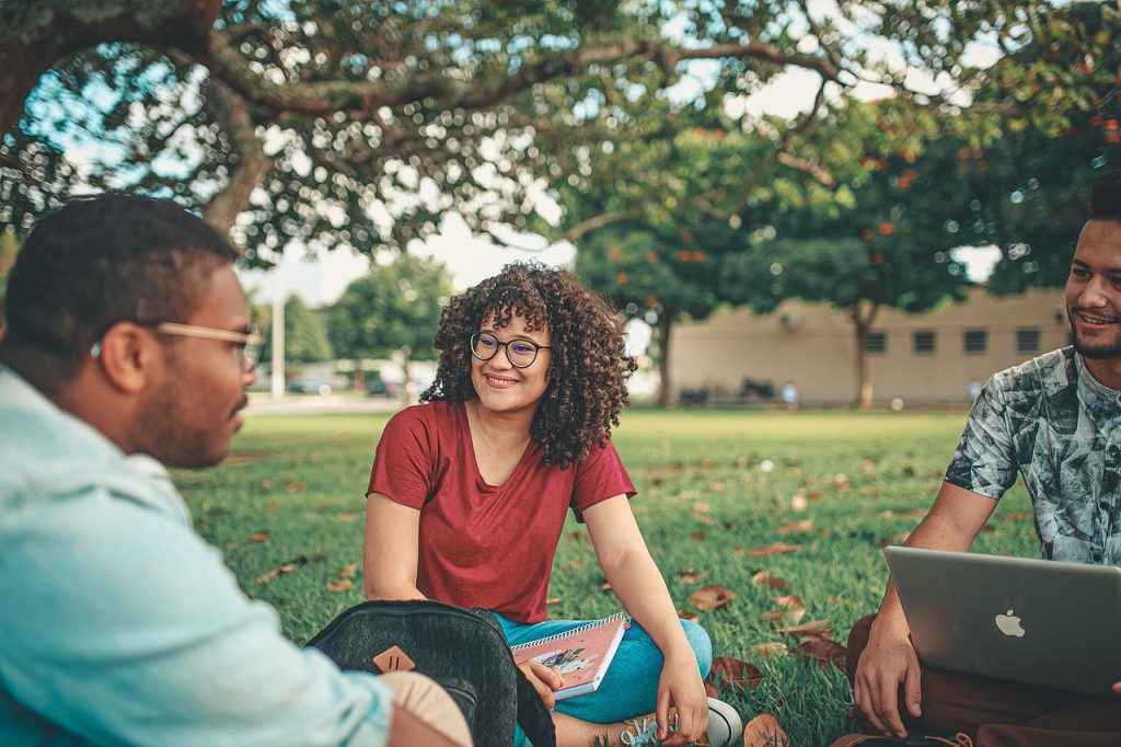 3 students sat out on a campus green.