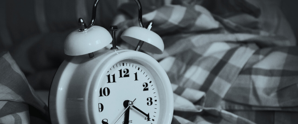 Image of a clock beside a bed.