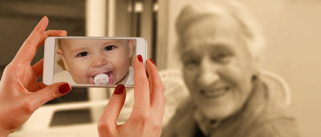 a person pointing a camera at an old person and seeing a baby in the viewfinder.