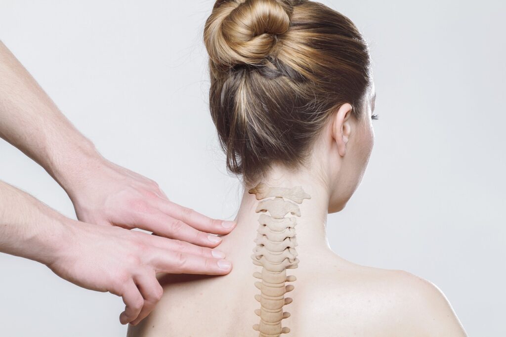 A persons spine with someone pressing near their shoulders.
