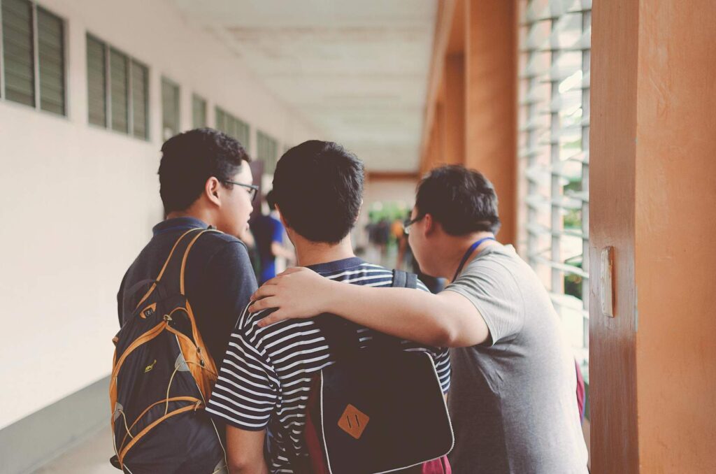 Three friends talking in a school corridor.