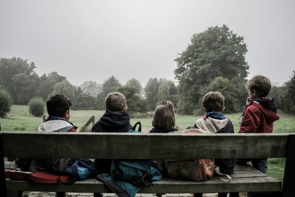 Group of children sitting on a park bench.