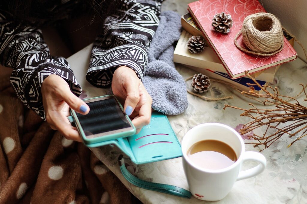 a person with a coffee sitting with their phone.