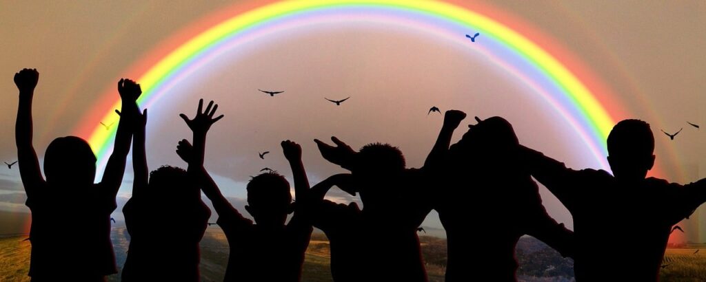 Silhouette of children in front of a rainbow.