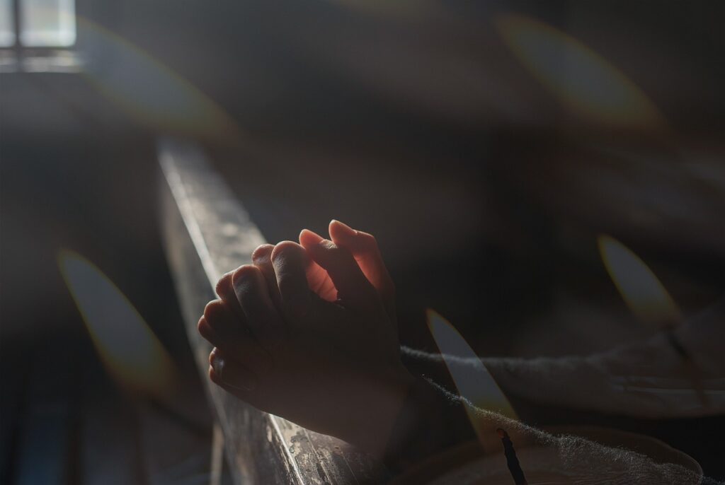 Hands clasped together in light from a window.