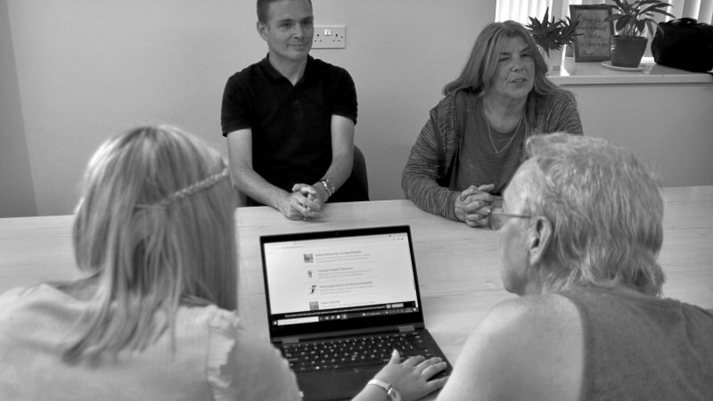 a group of people discussing with a laptop